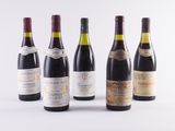 six bottles of wine are lined up in a row on a white surface
