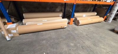 several rolls of paper are stacked on a shelf in a warehouse