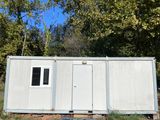 an image of a white portable home in the woods