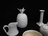 three white vases and a pineapple on a black table