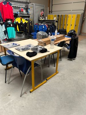une table sur laquelle sont posés de nombreux vêtements, dans une pièce