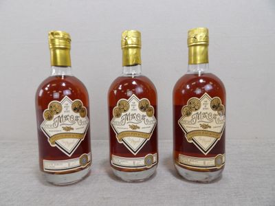 trois bouteilles d'alcool posées les unes à côté des autres sur une table