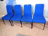 Quatre chaises bleues sont alignées contre un mur dans un salon