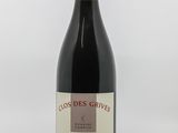 the bottle of red wine is sitting on a white surface