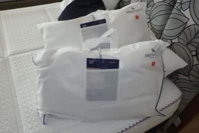 trois oreillers posés sur un lit, avec une étiquette de prix dessus