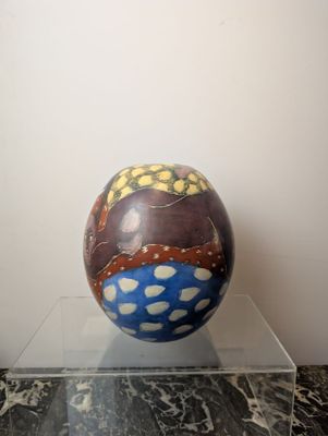 a colorful ball sitting on a clear stand on a marble floor