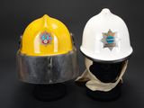 two white and yellow fire helmets sitting next to each other on a black surface