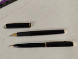 three pens sitting on a table next to a wallet