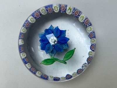 une fleur bleue sur une assiette blanche, accompagnée d'une feuille verte