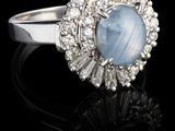 gros plan d'une bague avec une pierre bleue entourée de diamants