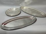 trois plateaux en argent et une assiette en argent posés sur une table blanche