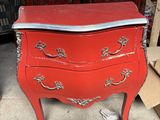 une vieille commode rouge au plateau argenté