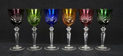 six verres à vin de couleurs différentes sont alignés