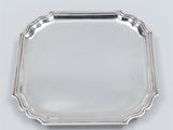 a silver tray with a handle on a white surface