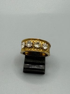 une image représentant une bague en or et diamants posée sur un morceau de bois noir