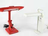 une lampe de bureau rouge qui se trouve à côté d'une lampe de bureau blanche
