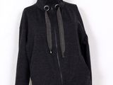 Le mannequin porte une veste noire sur laquelle est posé un sweat à capuche.