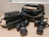 trois appareils photo et un sac pour appareil photo posés sur une table