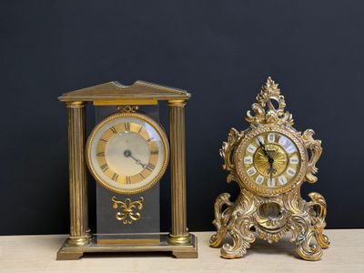 deux horloges posées sur une table, avec un mur noir en arrière-plan