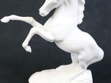 une statue blanche représentant un cheval debout sur ses pattes arrière