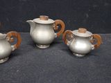 three silver teapots with wooden handles on a table