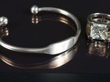 un bracelet en argent et une bague en diamant posés sur un fond noir