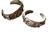 une paire de bracelets manchette en argent sur fond blanc