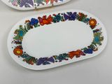 two plates with colorful designs on them sitting on a table