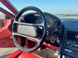 tableau de bord d'une voiture de sport rouge, avec un volant et des commandes sur le tableau de bord