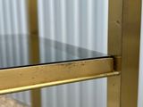 a close up of a gold metal shelf with a glass top