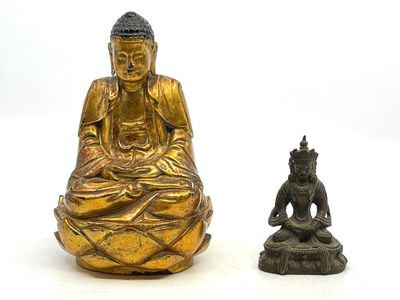 deux statues de bouddhas assis l'une à côté de l'autre sur une surface blanche
