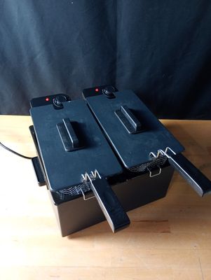 two deep fryers sitting on top of a wooden table