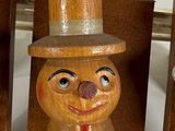 two wooden figurines of a man with a top hat and tie