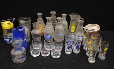Des bouteilles et des verres sont alignés sur une table devant un fond noir.