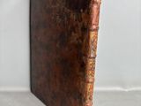 un vieux livre à la couverture brune posé sur une surface blanche