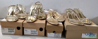 many pairs of gold shoes sitting on a box