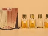 three small bottles of perfume sitting next to a box of perfume