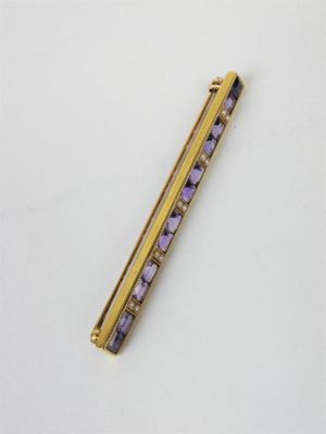 a close up of a purple and gold hair clip on a white surface