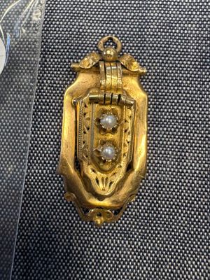 un pendentif en or orné d'une perle au centre