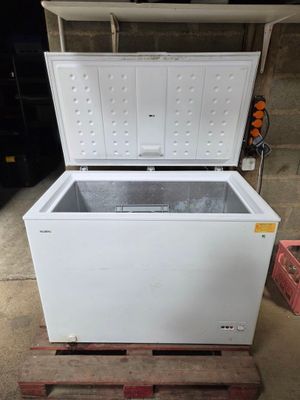 un congélateur coffre blanc posé sur une palette en bois