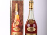une bouteille de cognac Hennessy à côté d'un carton
