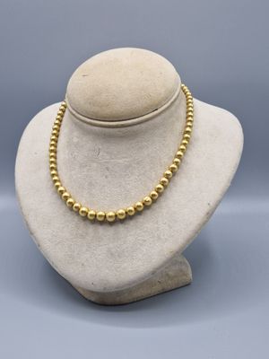 a gold beaded necklace on a mannequin display