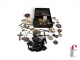 une boîte remplie d'objets en argent et en bronze posée sur une surface blanche