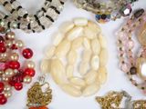many different colored beads and necklaces on a white surface