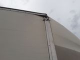 the side of a large white truck with a metal bar sticking out of it ' s side