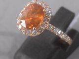 an image of a ring with a large orange stone surrounded by diamonds