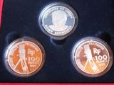 three coins are in a box with a red velvet cover