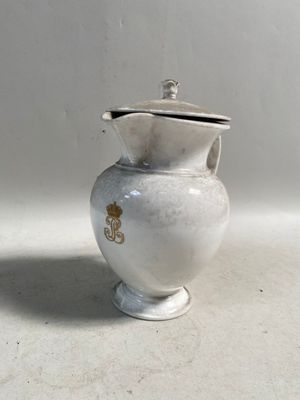 un petit vase blanc muni d'un couvercle, posé sur une table