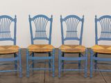 quatre chaises bleues sont alignées contre un mur blanc