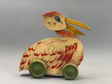 a wooden toy bird sitting on top of a toy car